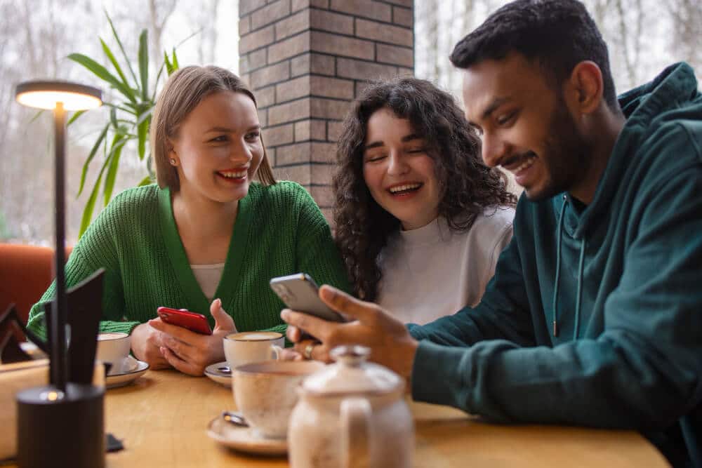 pessoas em uma padaria tomando chá e rindo, mexendo no celular, conectado na internet da empresa.