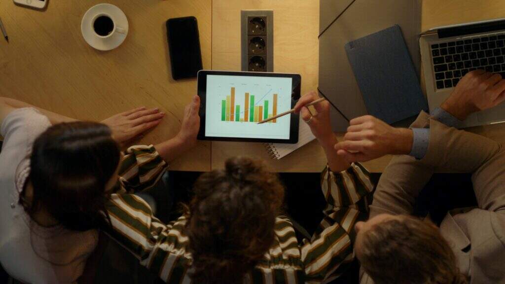 mulher olhando tela tablet com colegas equipe discutindo ideias de negocios de hotspot o que é com gráficos