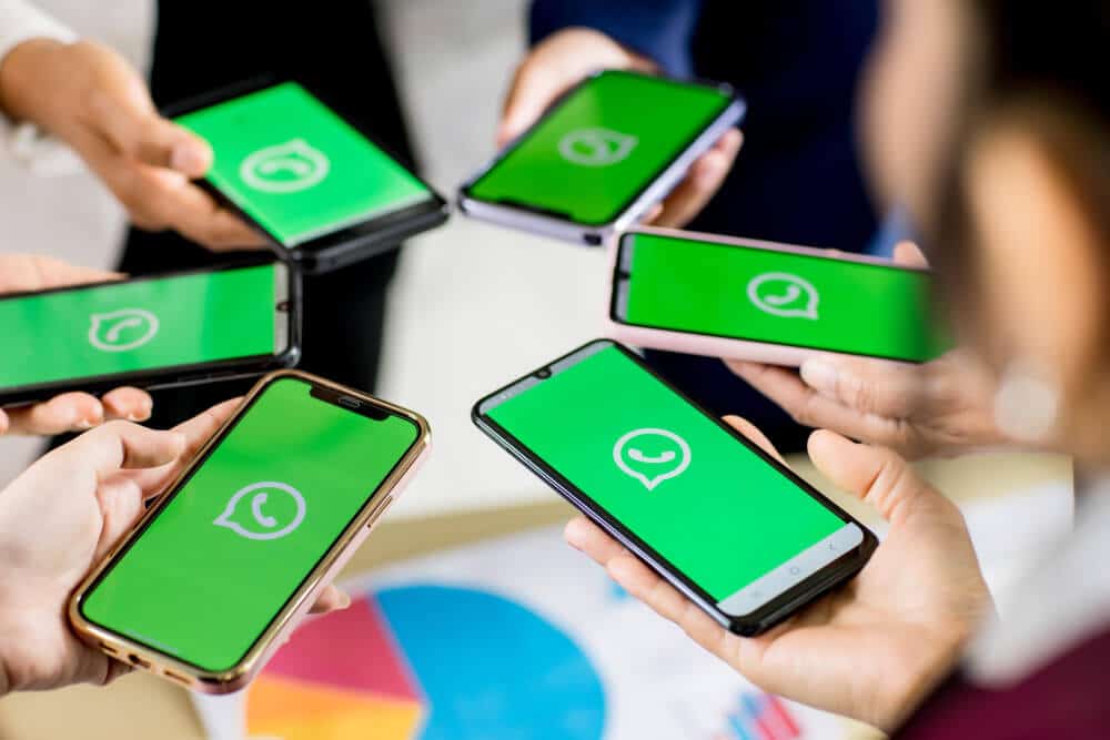 equipe empresarial segurando celulares e na mesa com gráficos, simbolizando o whatsapp para empresas como funciona