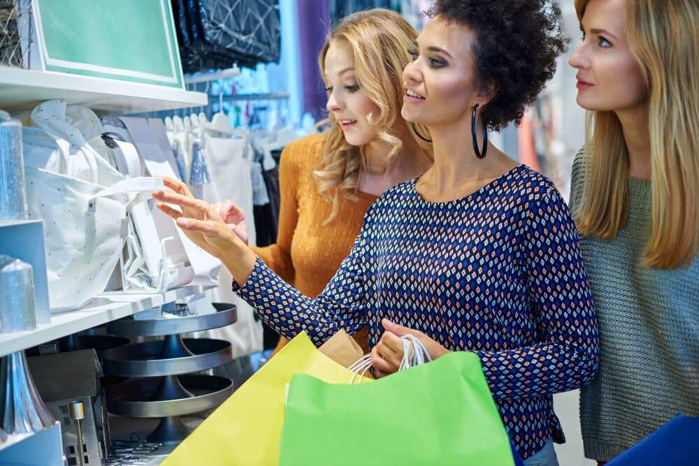 três mulheres fazendo compras em uma loja, simbolizando como as lojas podem e como gerar leads qualificados