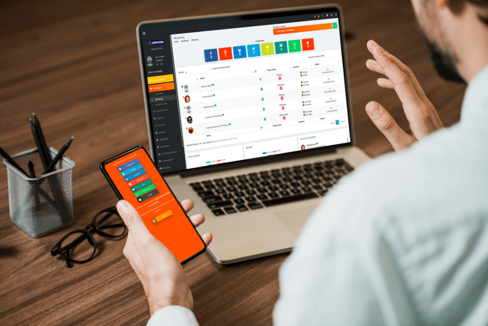 pessoa em seu escritório com notebook e celular na mão com imagens de dados de pessoas conectadas no hotspot social simbolizando o que é captive portal login