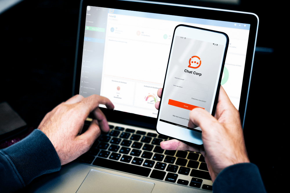 pessoa com notebook e celular na mão acessando um sistema de atendimento via WhatsApp, simbolizando Como usar o WhatsApp Business com múltiplos usuários