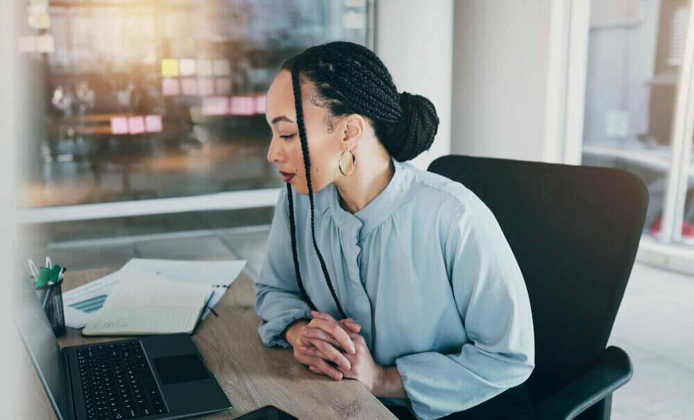mulher em um escritório olha seu computador em sua mesa, simbolizando o uso do WhatsApp Business API Oficial