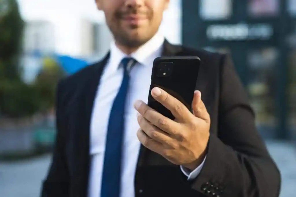 businessman outdoors looking his phone - DT Network